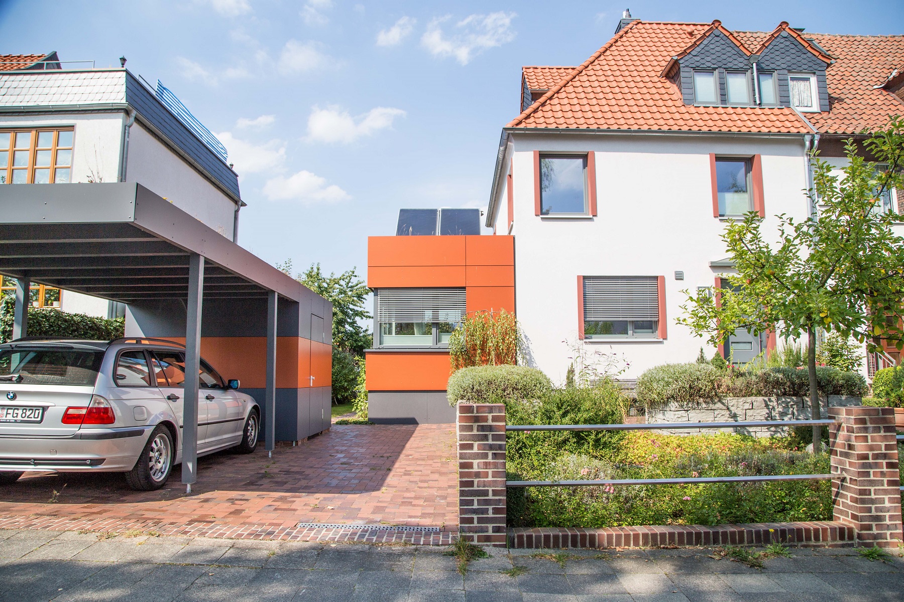 Reihenhaus in Hildesheim mit weißer Fassade, rotem Ziegeldach und orangefarbenem Anbau
